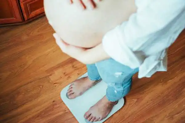 Image of woman weighing herself and experiencing weight gain through pregnancy Barry